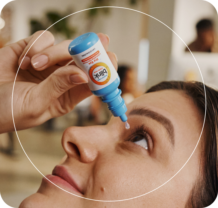Woman looking up, holding her eye open while using eye drop applicator.
