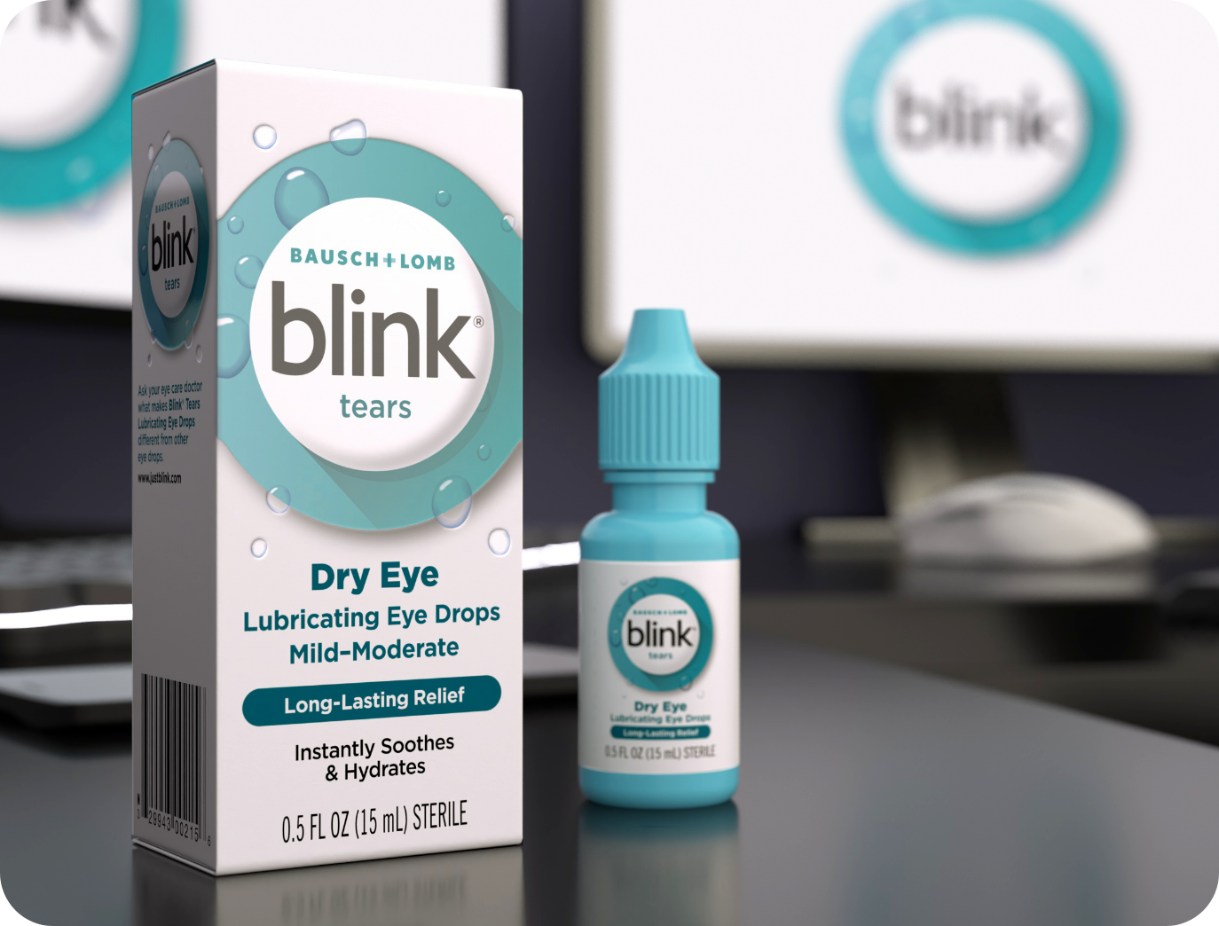 Blink Tears Lubricating Eye Drops bottle and package on a desk in front of a computer monitor