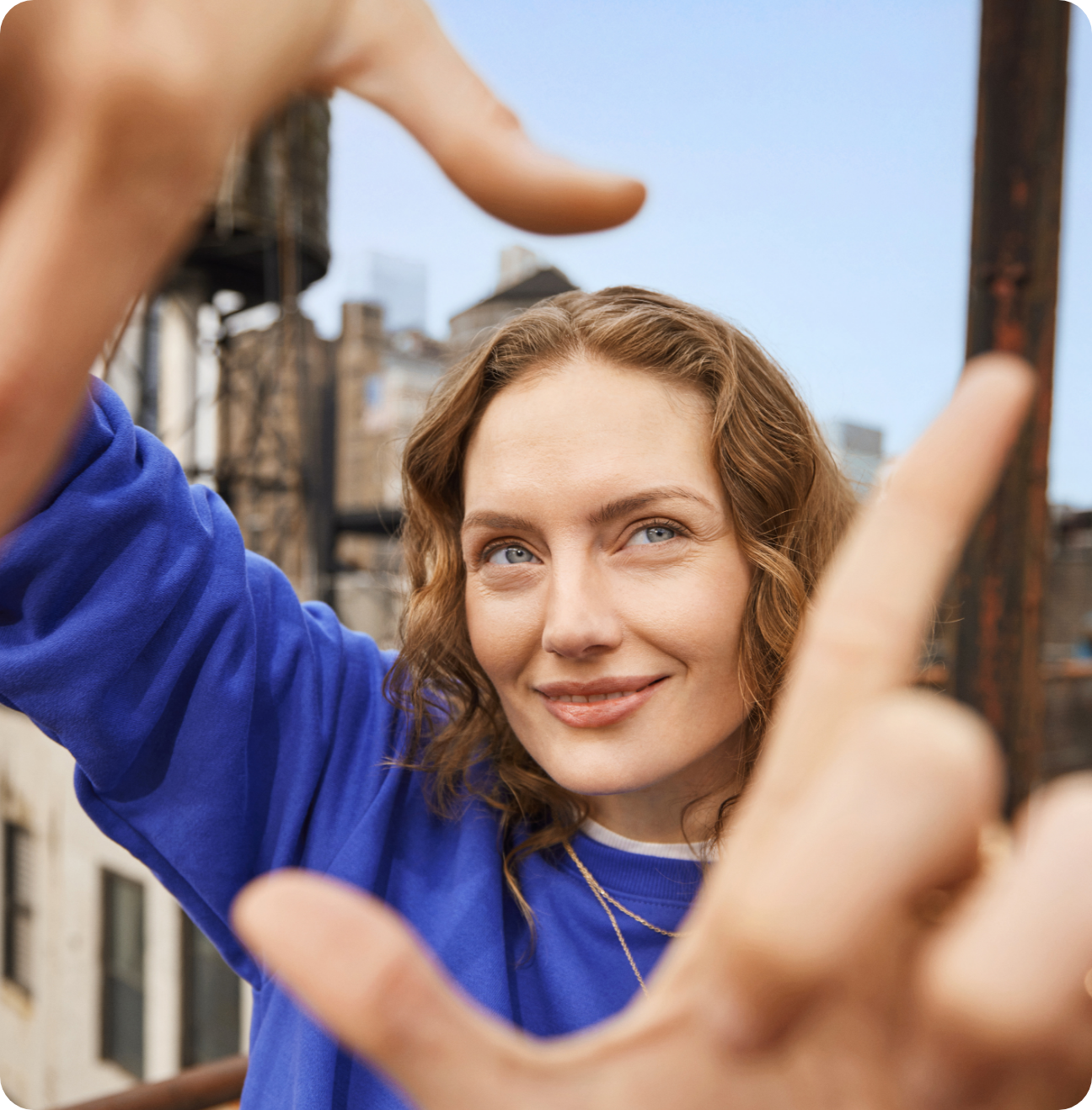 Woman framing her face with her hands, smiling at the camera.