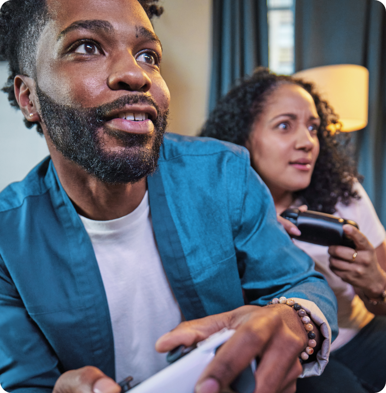 A couple playing video games at home, looking intently at the screen.